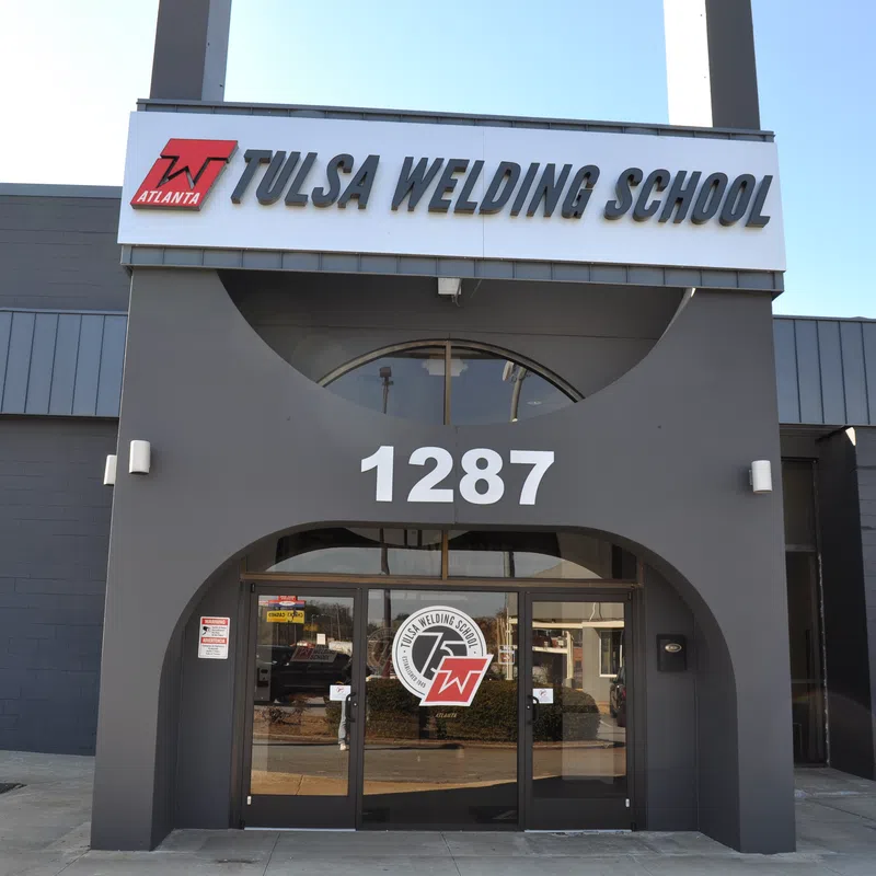 Front entrance of Tulsa Welding School with address 1287 and school logo on glass doors under clear sky.