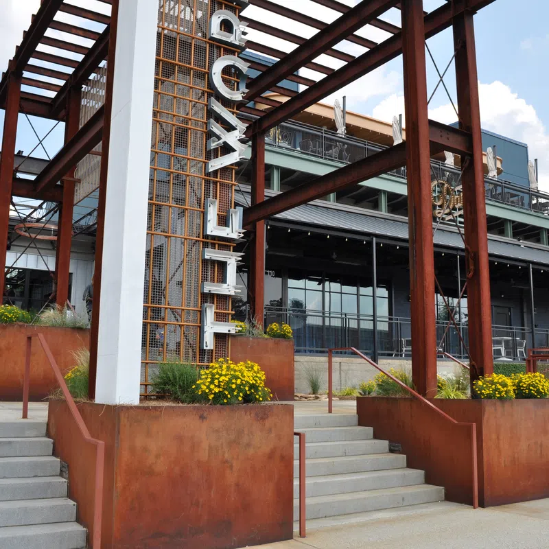 Rustic modern industrial building entrance with large steel beams and yellow flowers on sunny day