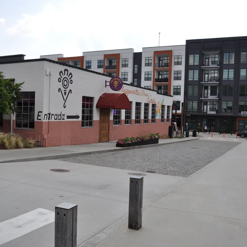 Exterior view of a restaurant with Entrada sign and nearby modern apartment buildings under clear sky