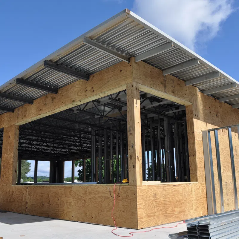 Commercial building under construction with plywood walls steel framing and metal roofing on a sunny day