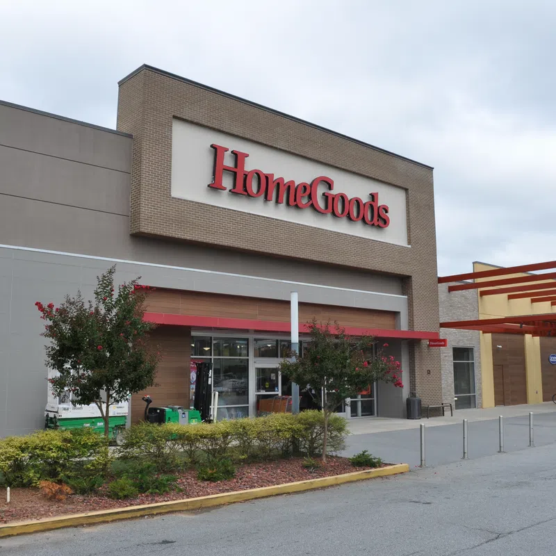 Exterior view of a HomeGoods store with clear signage and landscaped entrance under a cloudy sky.