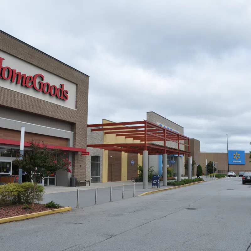 Exterior view of HomeGoods store next to Walmart in a shopping plaza under a cloudy sky.