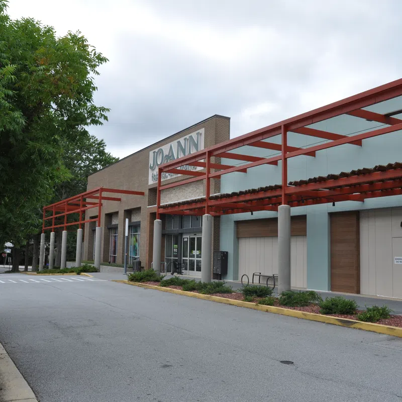Empty street view of a Jo-Ann fabric and craft store with red pergola and overcast sky