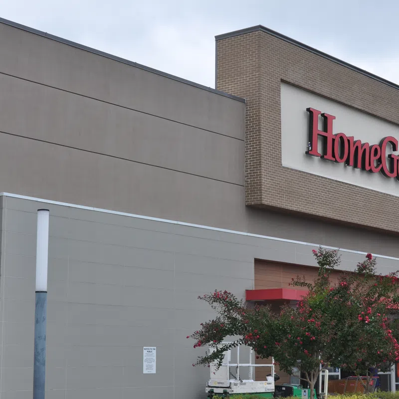Exterior view of HomeGoods store with large red sign and landscaping including flowering trees.