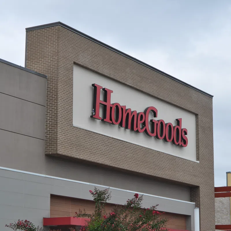 Exterior view of a HomeGoods store sign on a brick and beige building under a cloudy sky.