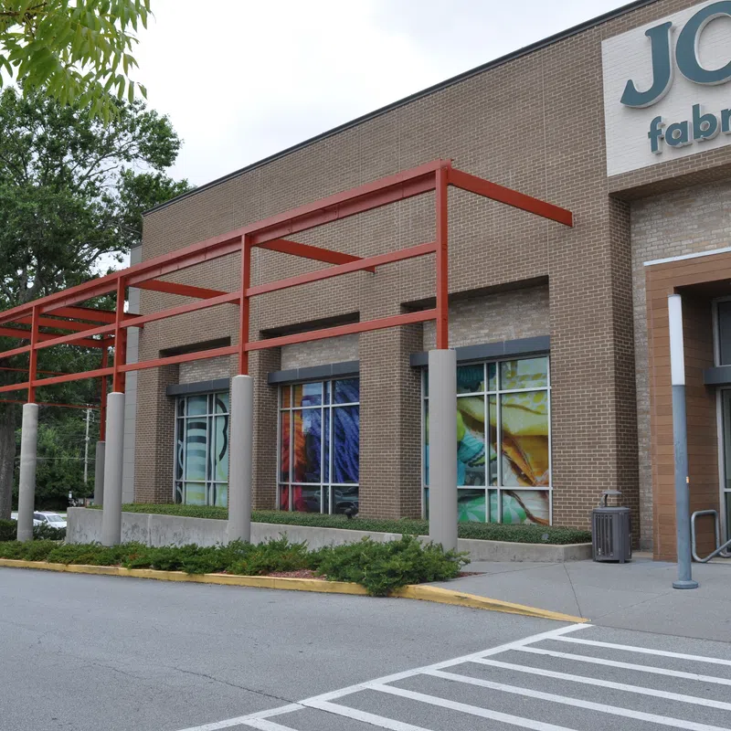 Exterior view of Jo-Ann Fabrics and Crafts store with brick facade and red metal awning structure.