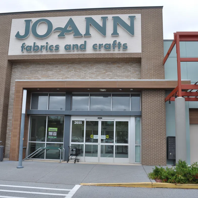 Facade of Jo-Ann Fabrics and Crafts store with glass entrance and exterior signage on a cloudy day