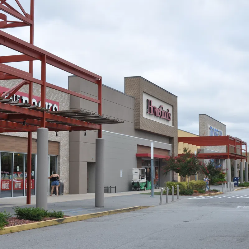 Shopping center exterior with HomeGoods and Walmart stores under a cloudy sky with parked cars.