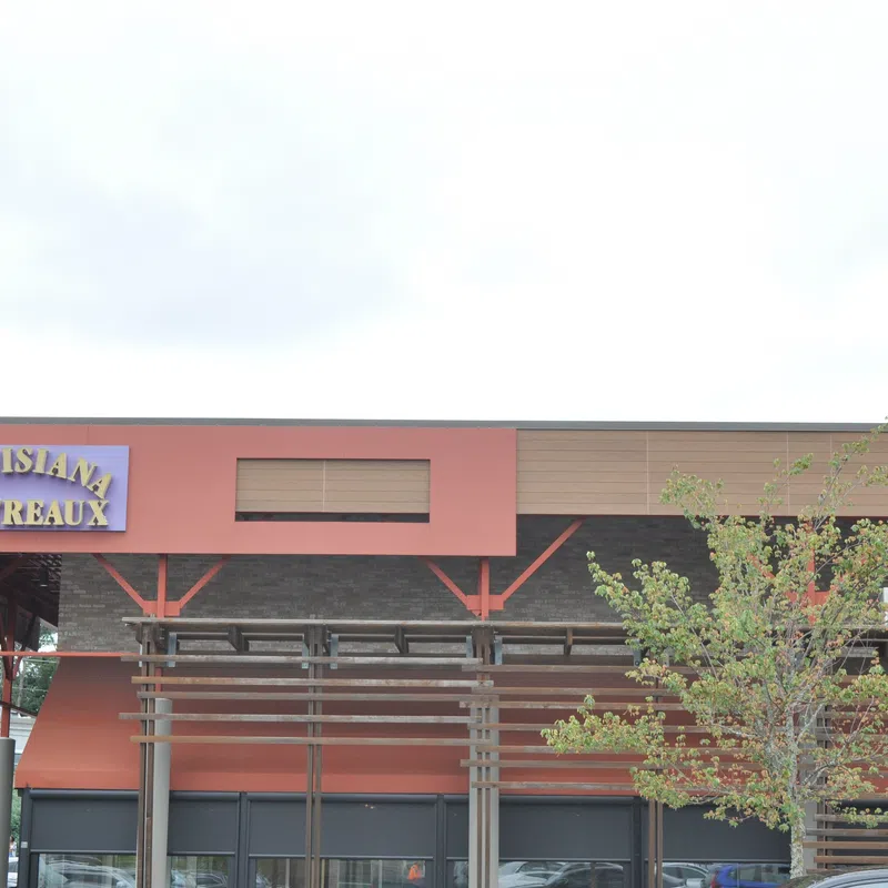 Louisiana Bistreaux restaurant exterior with sign, orange awnings, wooden pergola, and a tree in front.