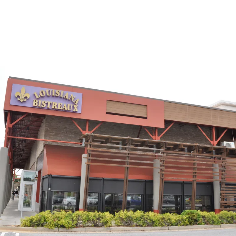 Exterior view of Louisiana Bistreaux restaurant with red and brown facade and wooden pergola structure.