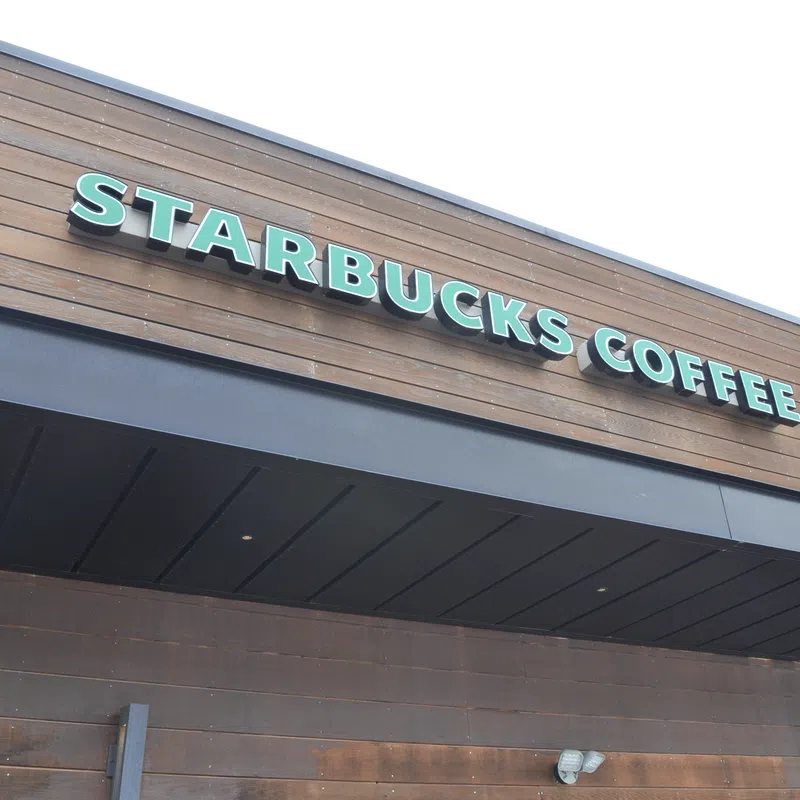 Exterior view of a Starbucks Coffee shop with wooden paneling and green signage on a clear day