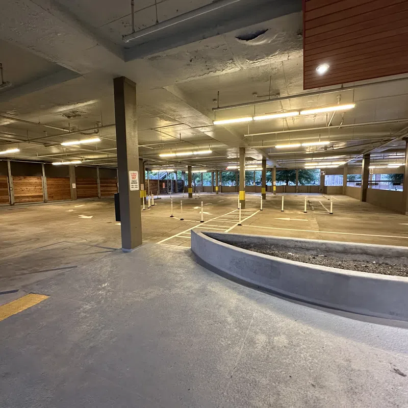 Empty indoor parking garage with concrete pillars, yellow markings, and overhead fluorescent lights