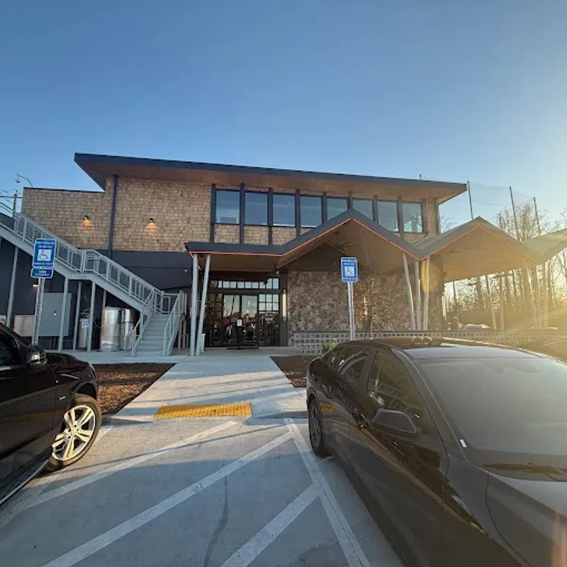 Modern two-story building with stone and wood accents, accessible ramps, parked cars, and bright sunset lighting
