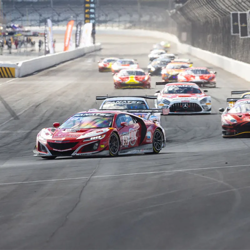 High-speed sports cars racing closely on a professional racetrack during a competitive event.