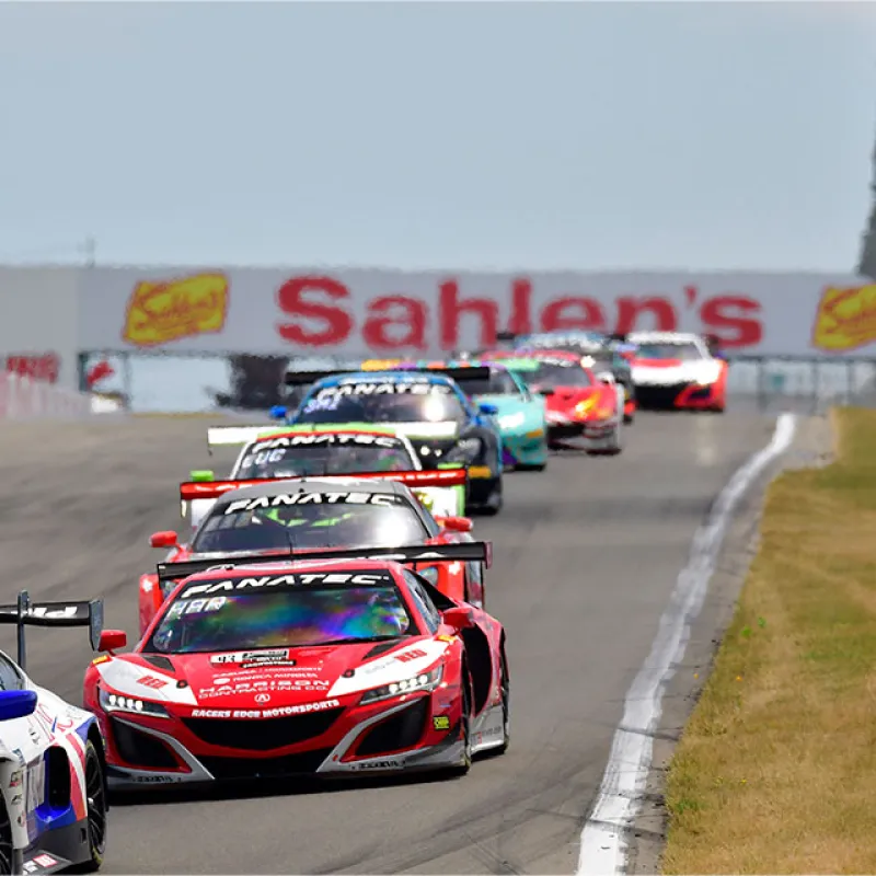 Race cars competing on a racetrack under the Sahlen's banner during a motorsport event.