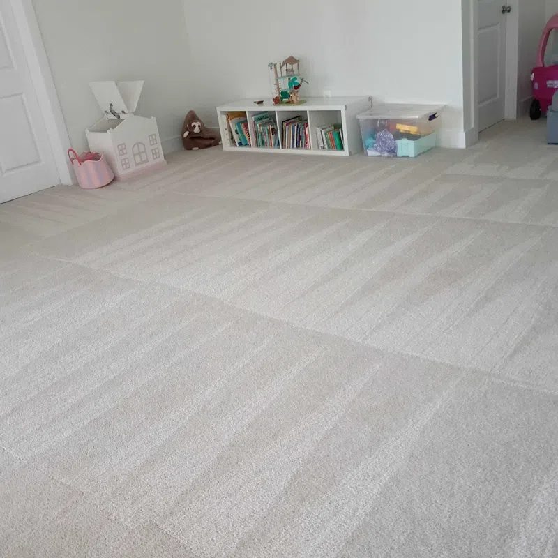 Bright children's playroom with clean, patterned beige carpet, white walls, toy storage, and bookshelves.