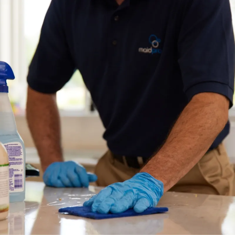 a man wearing gloves and a blue shirt working on a piece of paper