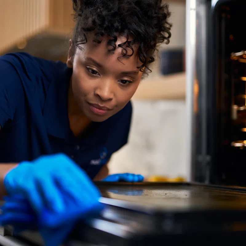 MaidPro St. Petersburg house cleaner scrubbing a dirty oven