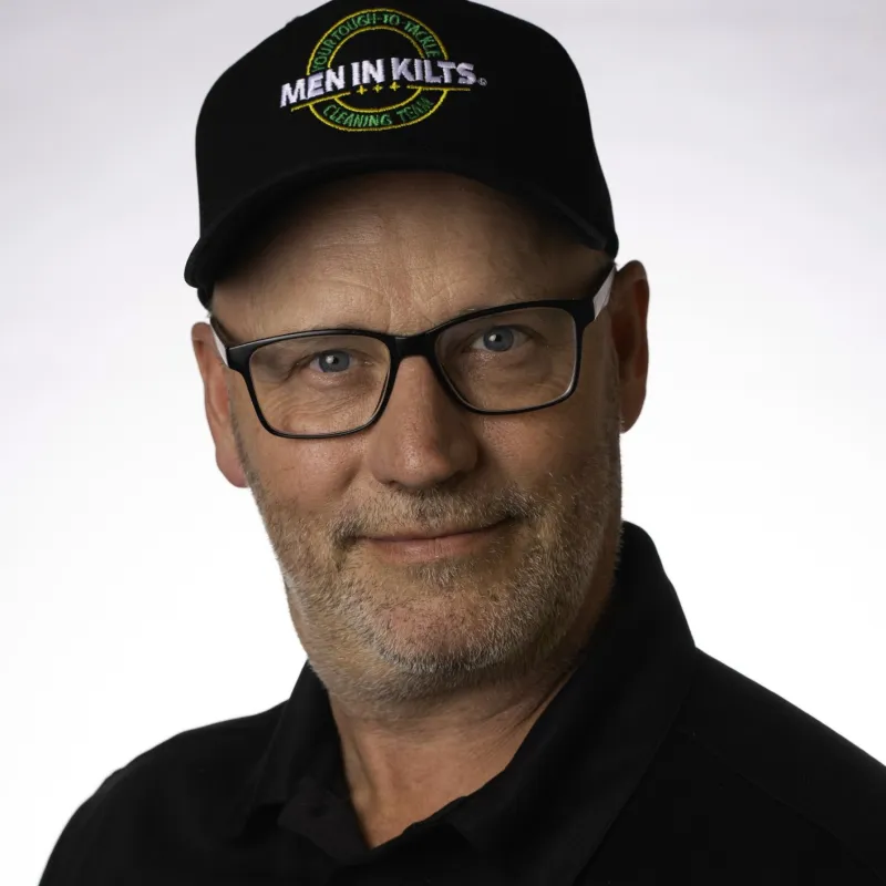 Man wearing black Men In Kilts cap and polo shirt with company logo on a white background