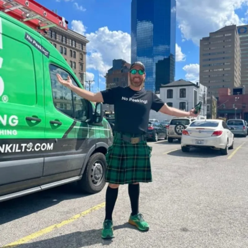 a person in a kilt standing next to a green truck