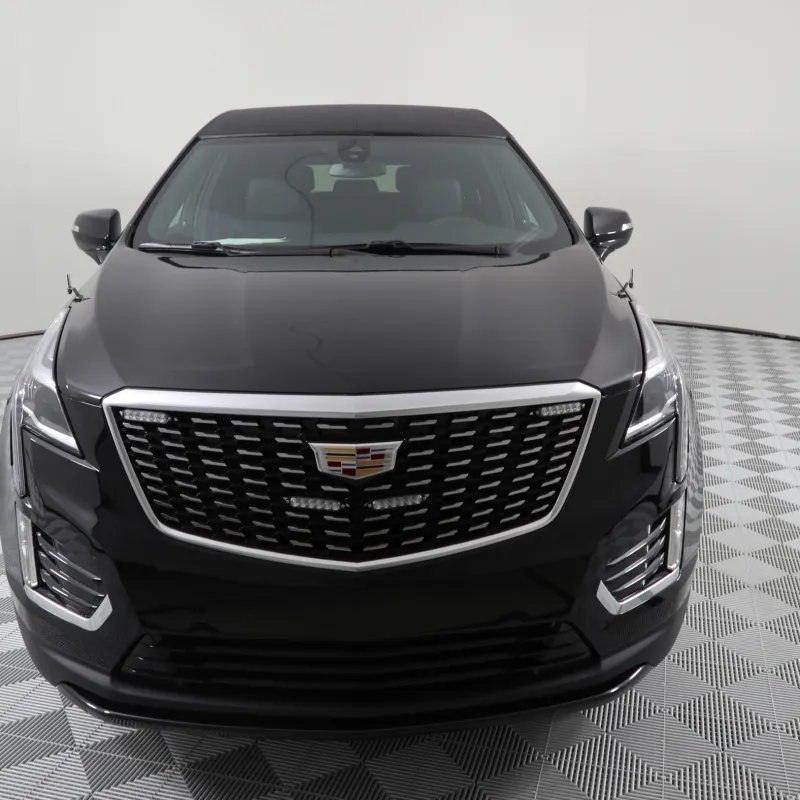 Front view of a sleek black Cadillac XT5 SUV on a checkered floor background.