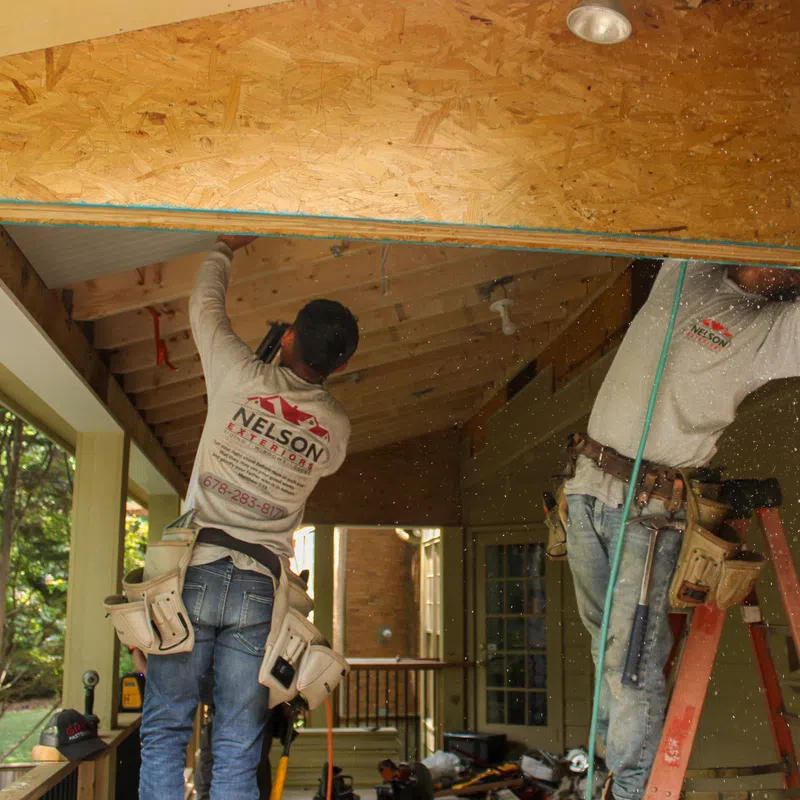 Two professional contractors from Nelson Exteriors working on an outdoor porch ceiling installation in Marietta, Georgia, highlighting high-quality craftsmanship and dependable service.