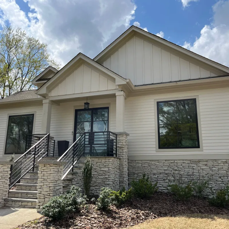 A beautiful modern craftsman home featuring cream lap siding, vertical gables, and stone veneer accenting, highlighting James Hardie vs other siding materials in Marietta by Nelson Exteriors.