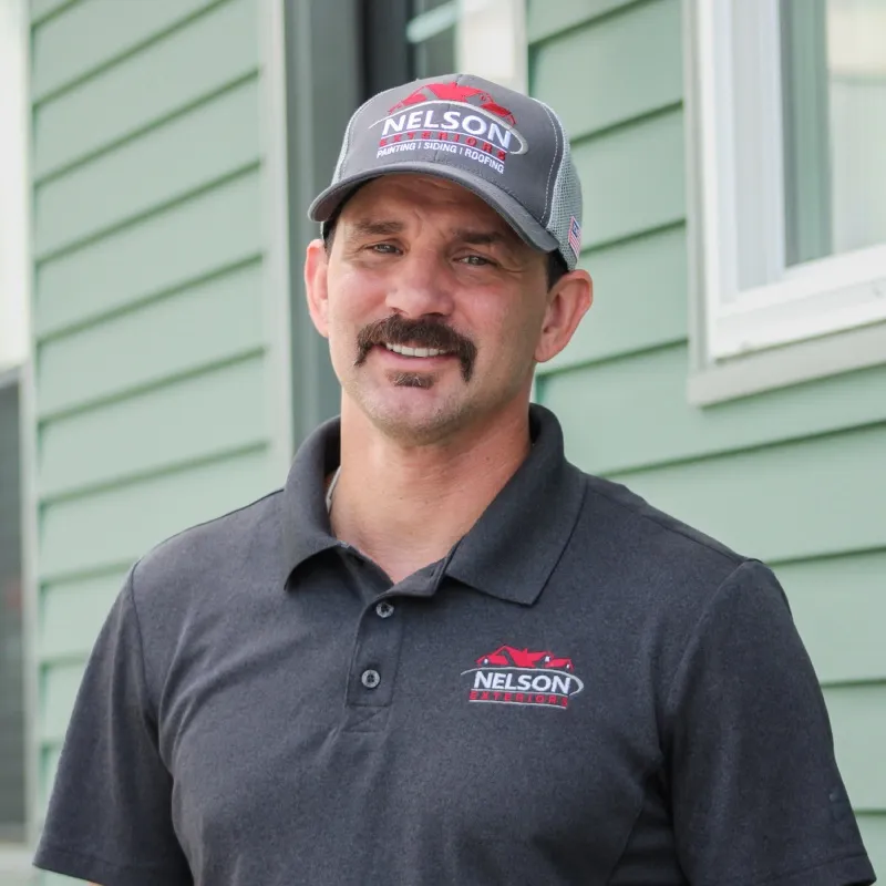 Chris Hall of Nelson Exteriors smiling outside a home