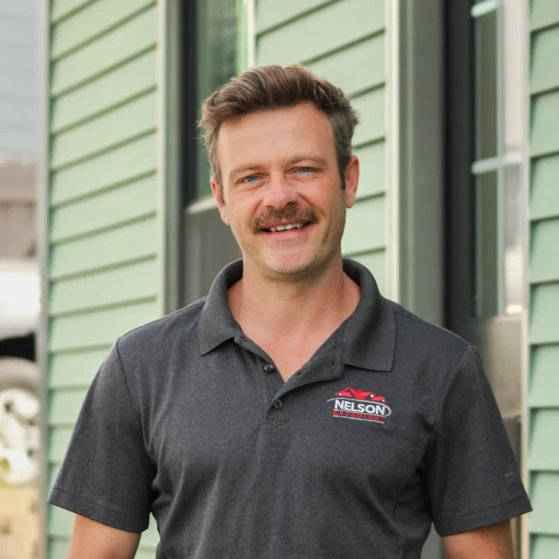 Josh Motes wearing a Nelson Exteriors polo shirt, smiling outdoors by Nelson Exteriors