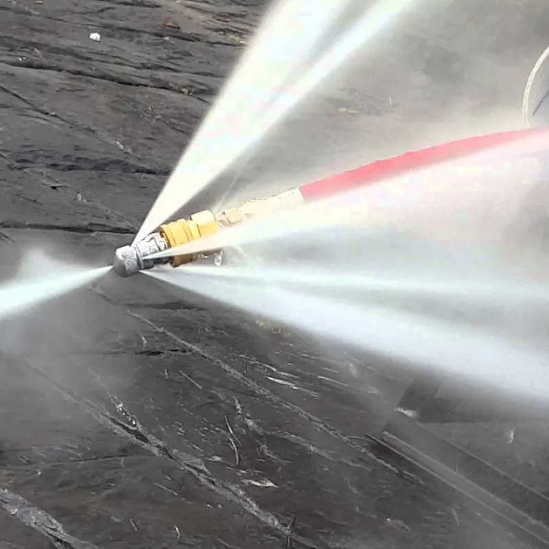 High-pressure water jet nozzle spraying multiple streams for surface cleaning on dark stone pavement.