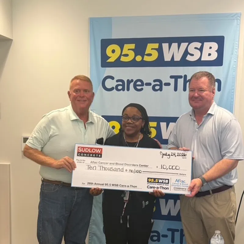 Three people holding a large $10,000 donation check for 95.5 WSB Care-a-Thon cancer and blood disorders fundraiser.