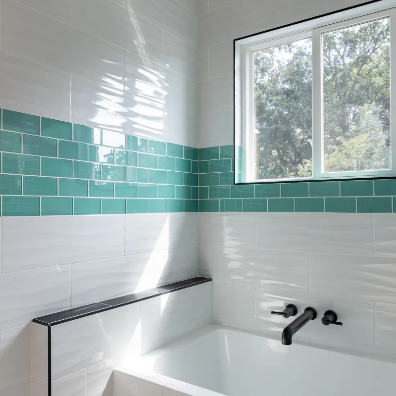 Modern bathroom with white and teal wall tiles, black faucet, bathtub, and natural light from window.