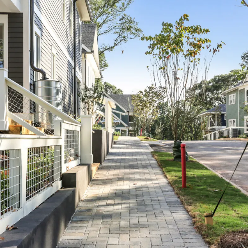 a sidewalk with a fence and trees
