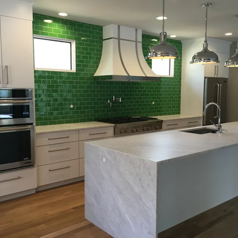 a kitchen with green and white tiles