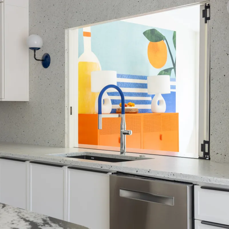 Modern kitchen with white cabinets, speckled countertop, stainless steel appliances, and a colorful mural in the background.