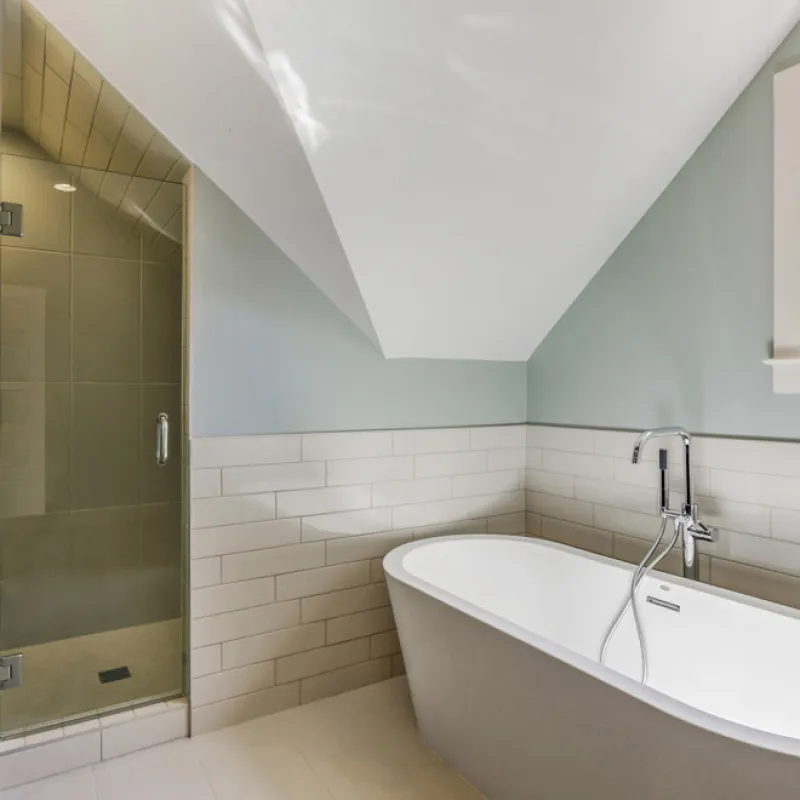a bathroom with a tub and a shower unit