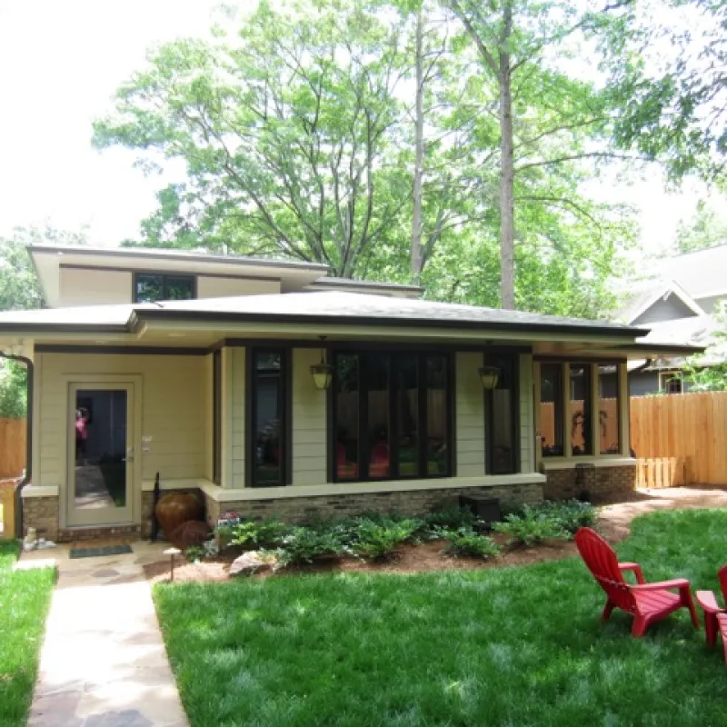 a small house with a fence and lawn