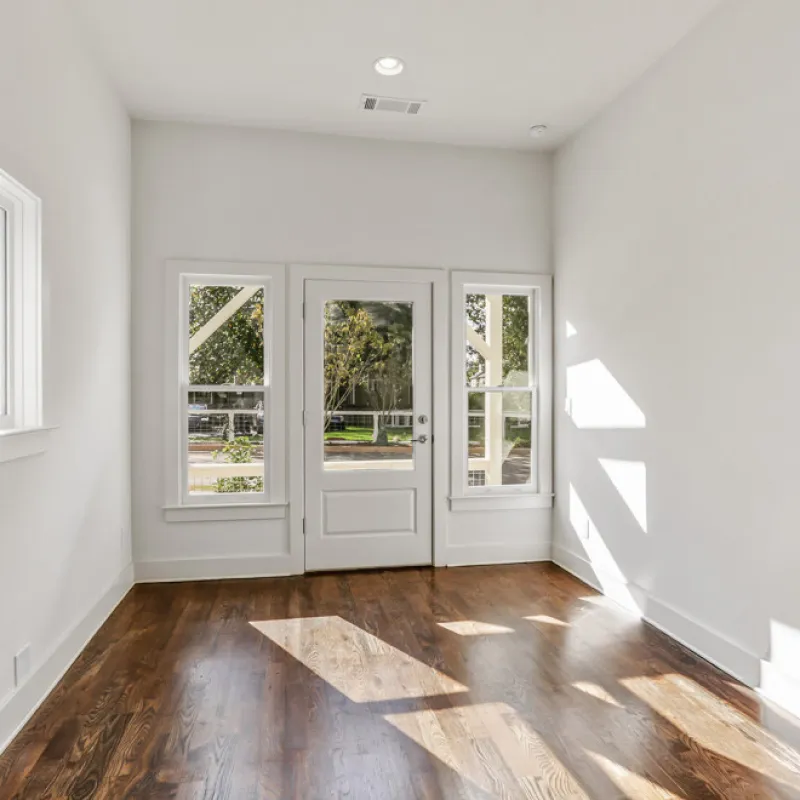 a room with white walls and a wood floor with a white door