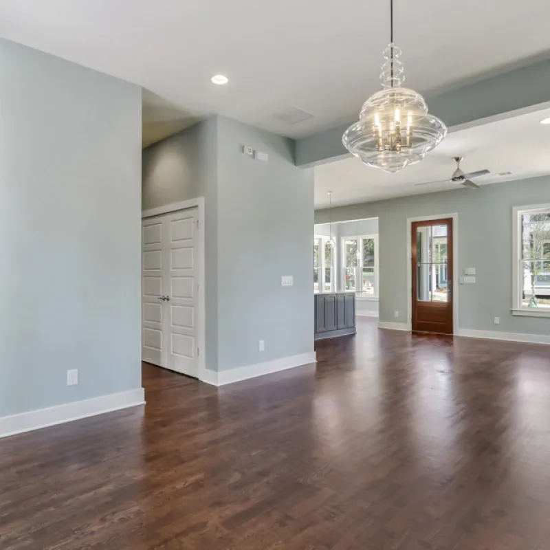 a large empty room with a wood floor and a chandelier