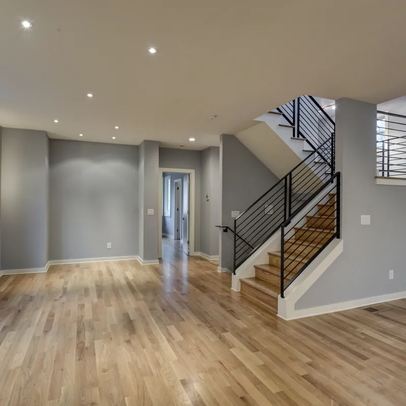 a large empty room with a wood floor and a wood staircase