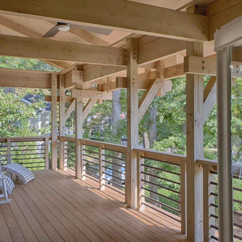 a wooden deck with a wood railing and trees