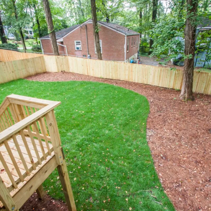 a fenced in yard with a wooden bench and a house