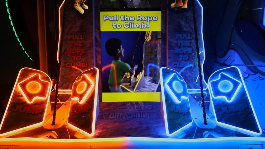 Colorful arcade climbing game with neon orange and blue lights and a sign that says Pull the Rope to Climb