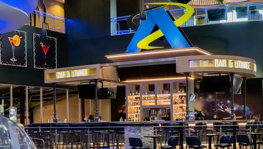 Modern bar interior with illuminated shelves, tall chairs, and vibrant lighting in a sleek lounge setting