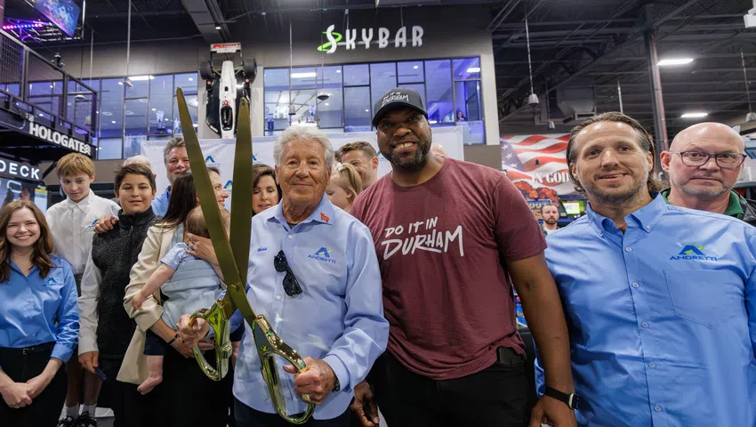 Group of people at a ribbon-cutting event with large golden scissors in front of Skybar venue