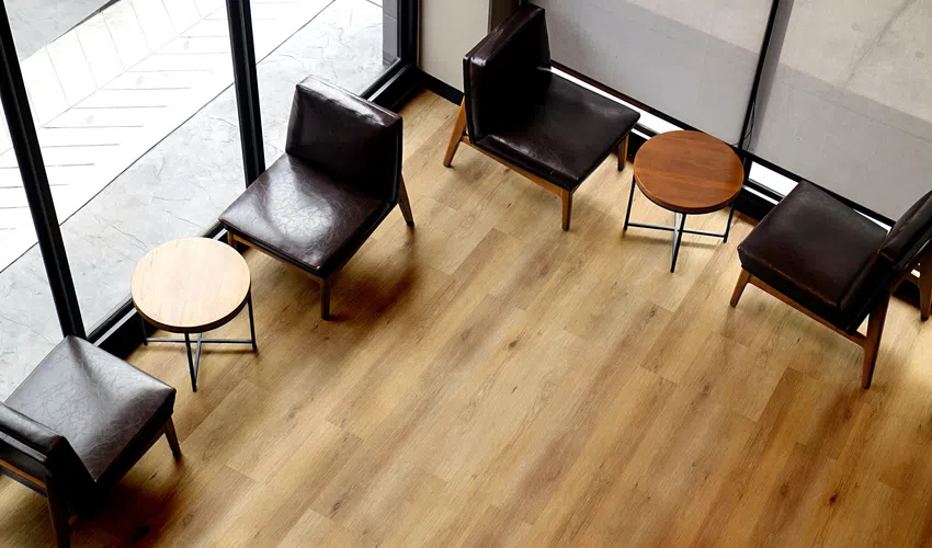 Top view of modern lounge area with black leather chairs and round wooden tables on light wood floor