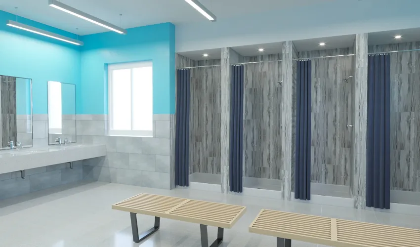 Bright, clean locker room with wooden benches, blue curtains on showers, large mirrors, and turquoise accent wall.