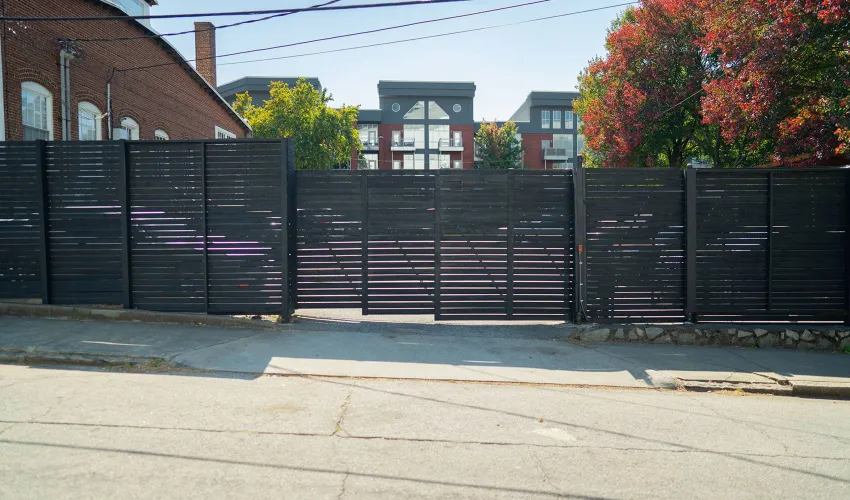 a black fence with a gate and a building in the background