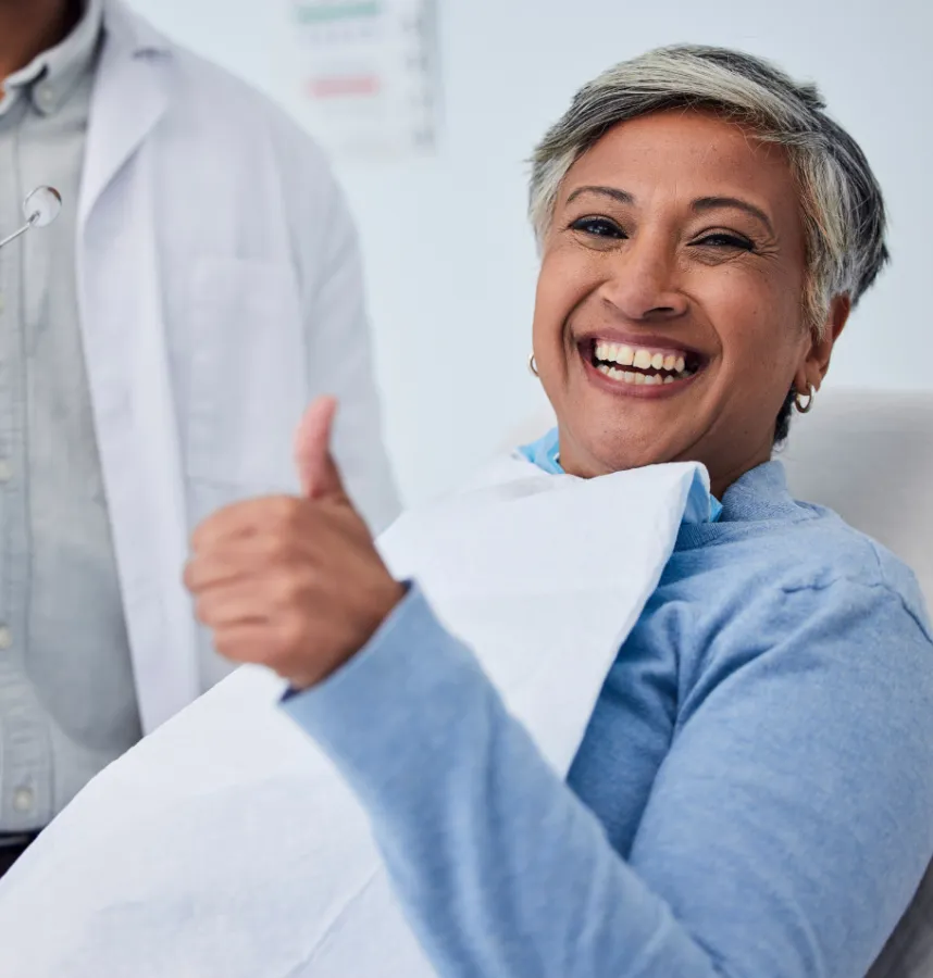 a person smiling with a thumbs up in dentist chair