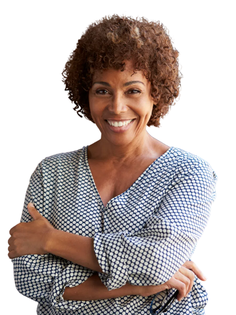 Smiling middle-aged woman with curly hair wearing a patterned blouse with arms crossed confidently.
